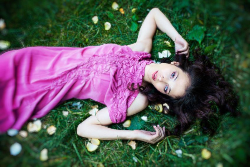 beautiful young woman in elegant summer dress lie in grass