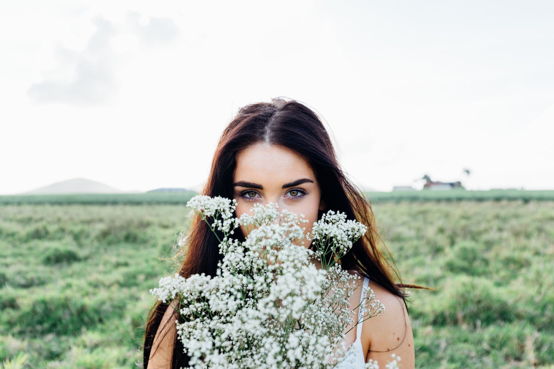 young woman pretty girl flowers white bouquet spring green grass countryside nature brunette long hair smile smiling happy joy psychic